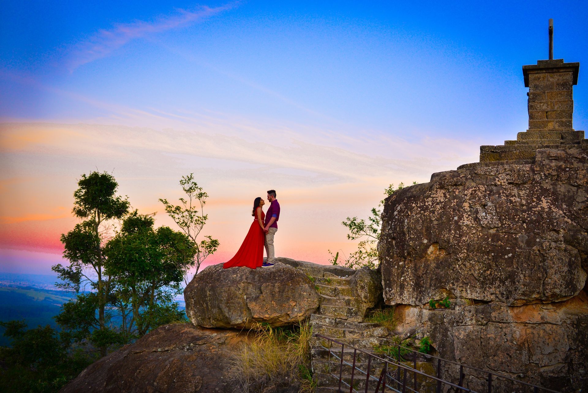 Casal em ensaio ao pôr do sol sobre formação rochosa, fotografado pelo Studio 9